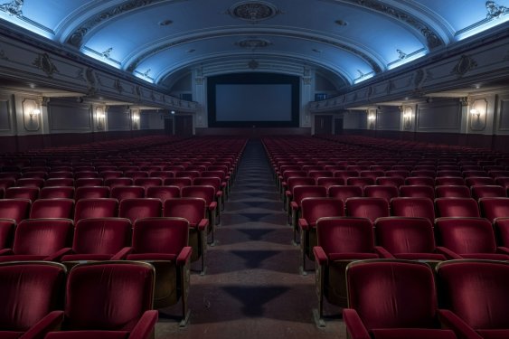 Sweeping perspective of vintage cinema auditorium velvet seats under ambient blue light
